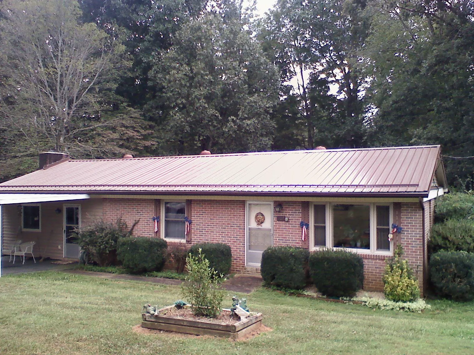 Bronze metal roof on a brick ranch home with a carport in Argusville