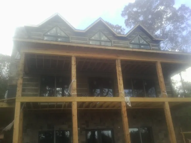 Dormers and porch framing on a large log home under construction — Roof Coating work by our crew in Argusville