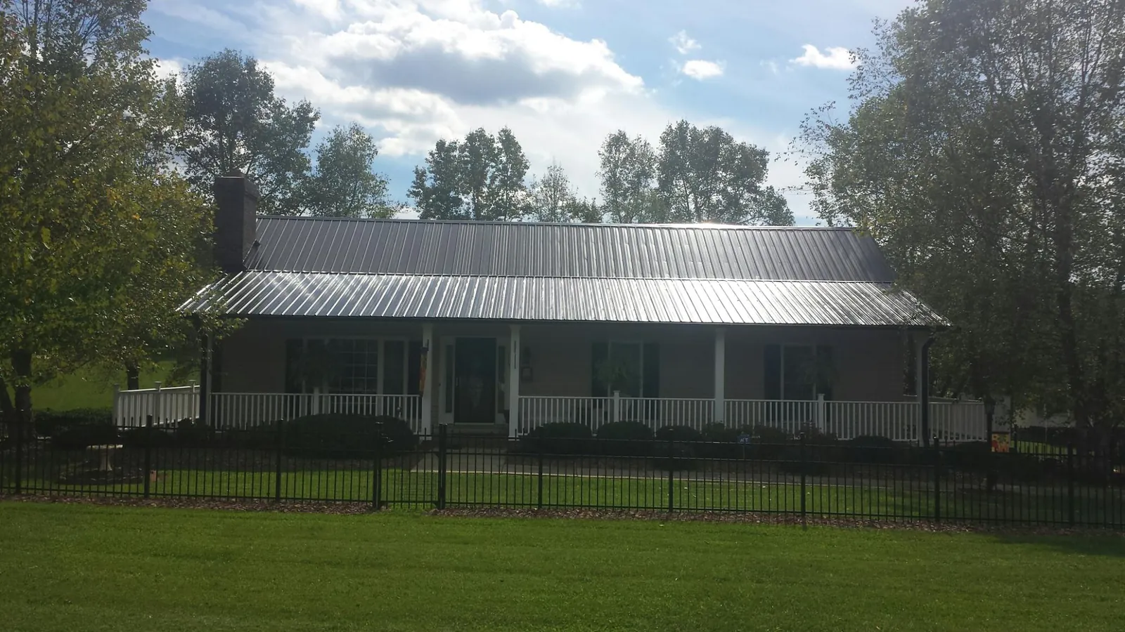 Gray metal roof on a brick ranch with a full width front porch — Gutter Guard Installation work by our crew in Argusville