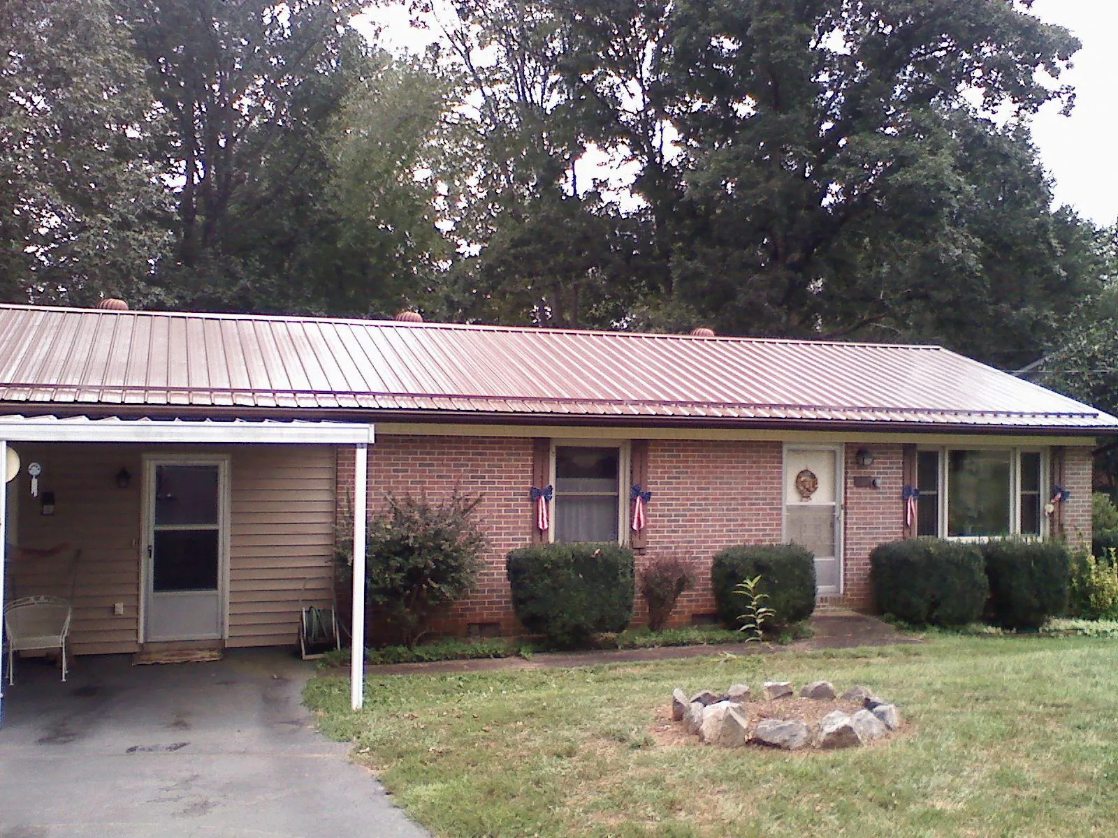 Bronze metal roof and carport on a brick ranch home — Roof Repair work by our crew in Argusville