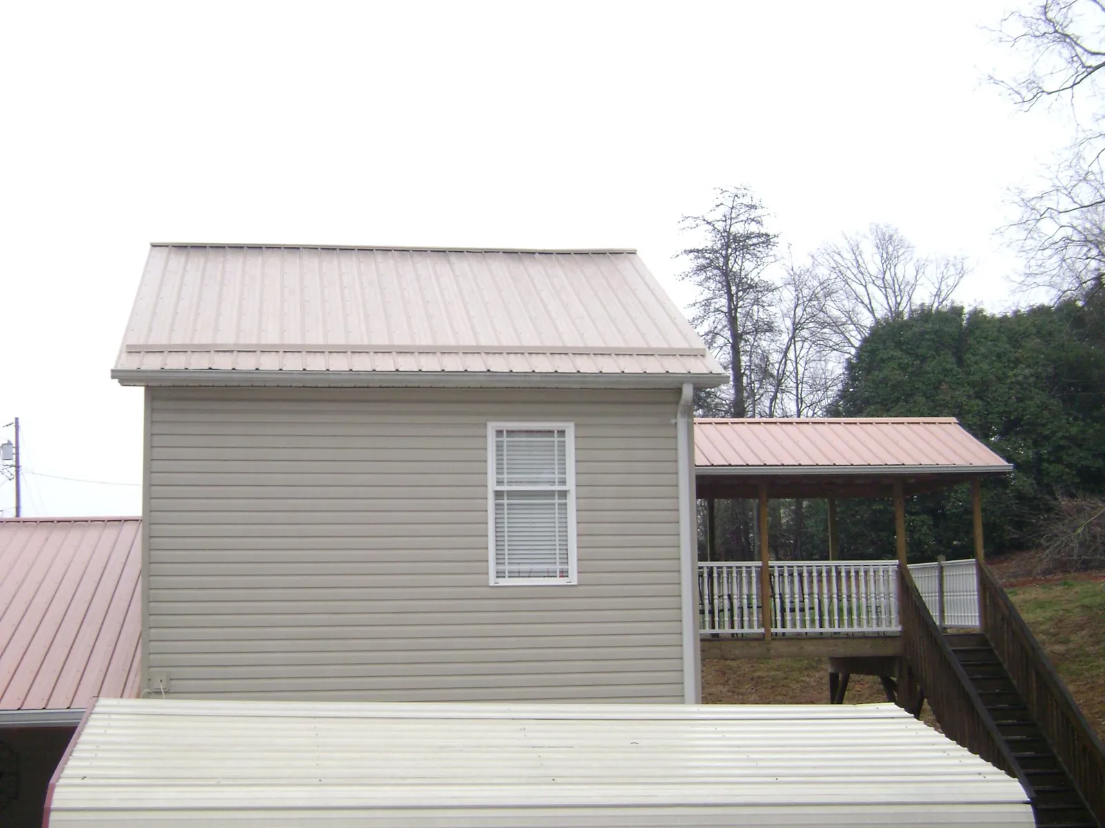 Tan metal roofs on a two story addition and attached porch, from a Roof Replacement job in Argusville