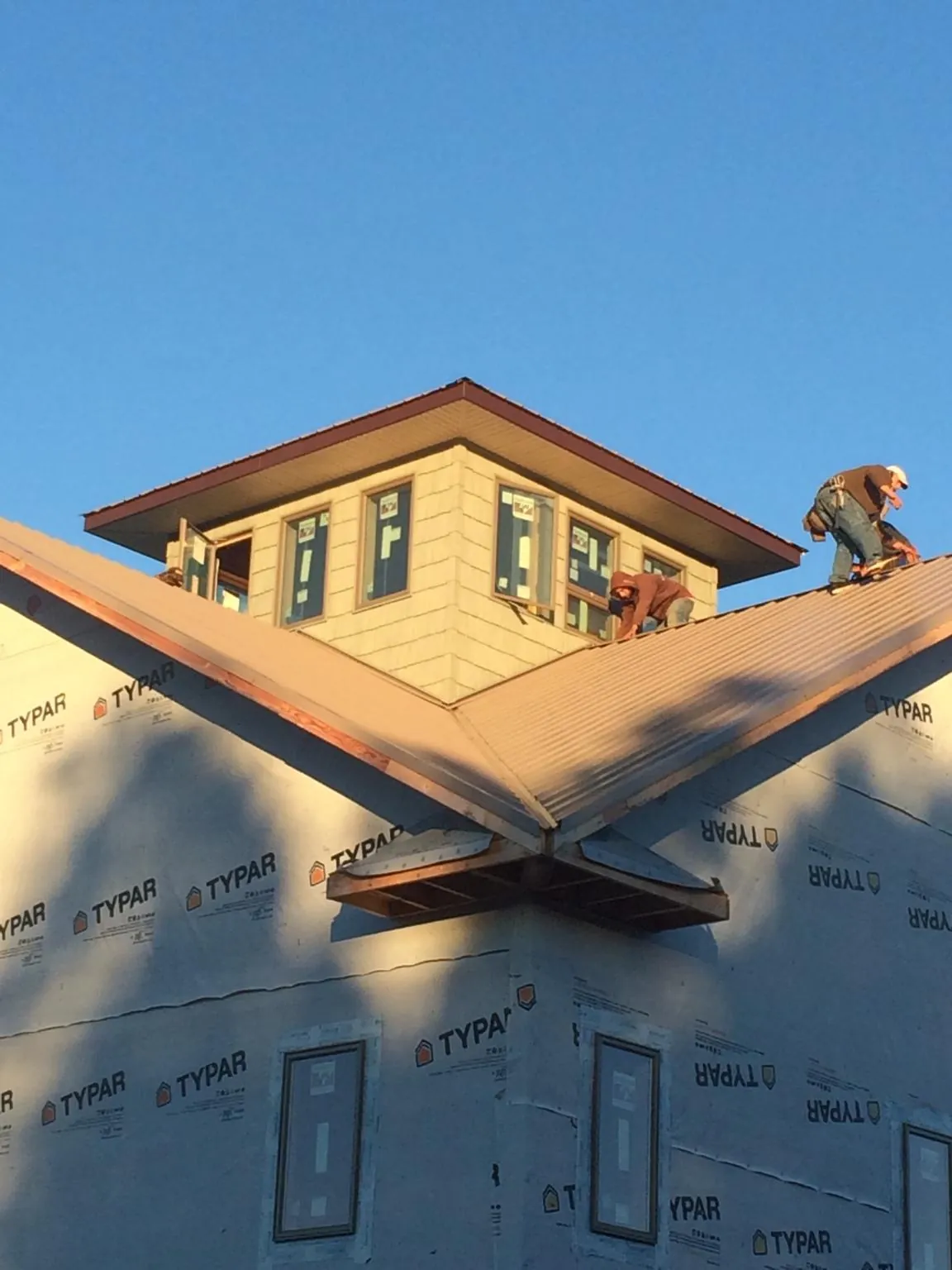 Roofers working around a rooftop cupola on a new metal roof at sunset — Roof Waterproofing in Argusville by Roofing Brothers